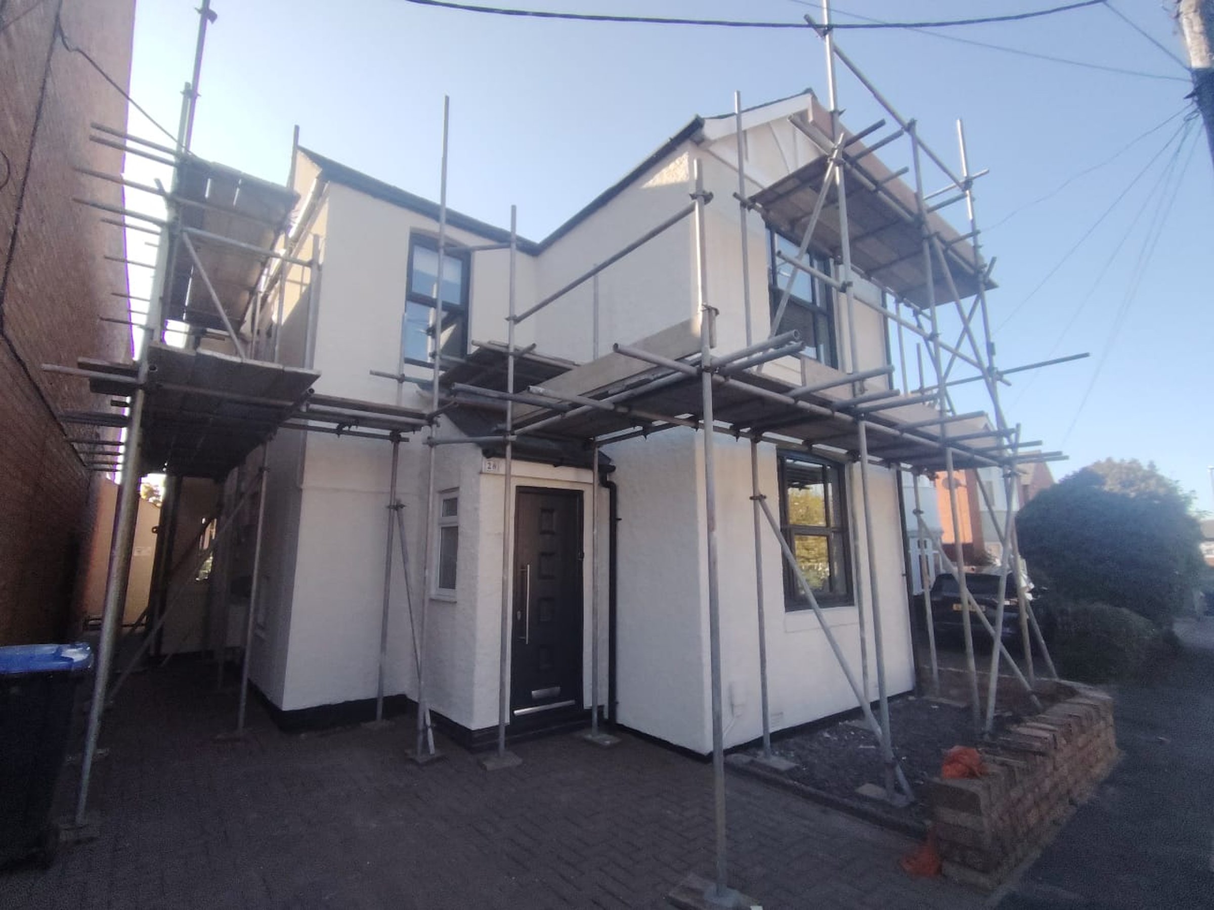 House undergoing re-rendering with full scaffold and fresh render being applied